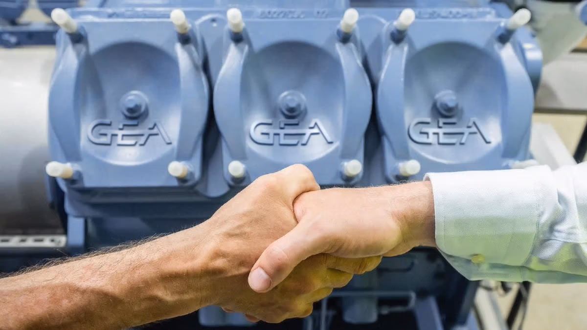 Zwei Männer beim Handschlag vor einem GEA Kolbenkompressor für die industrielle Kältetechnik